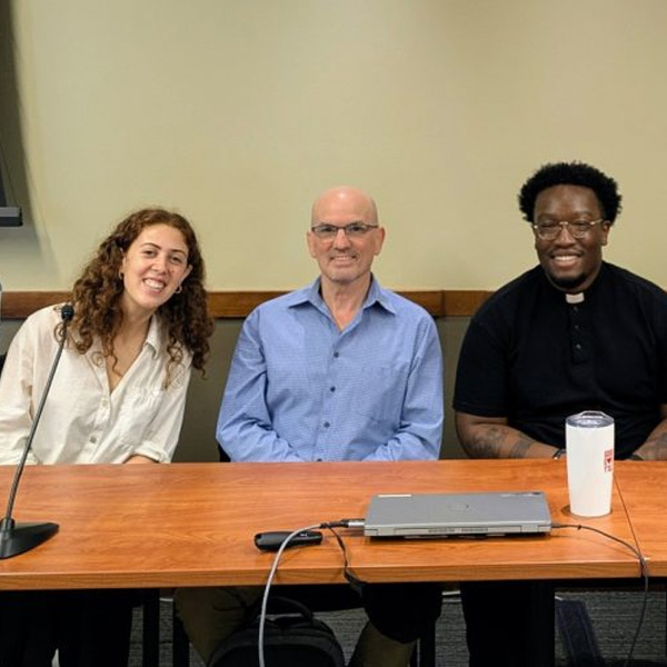 Three people seated at table smiling for a picture.